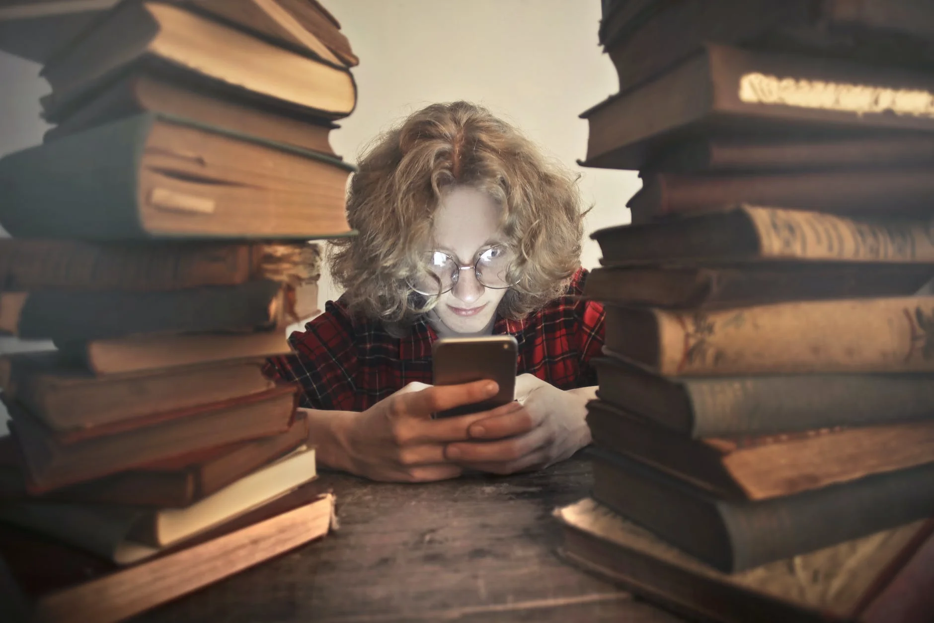 student browsing smartphone at table with books