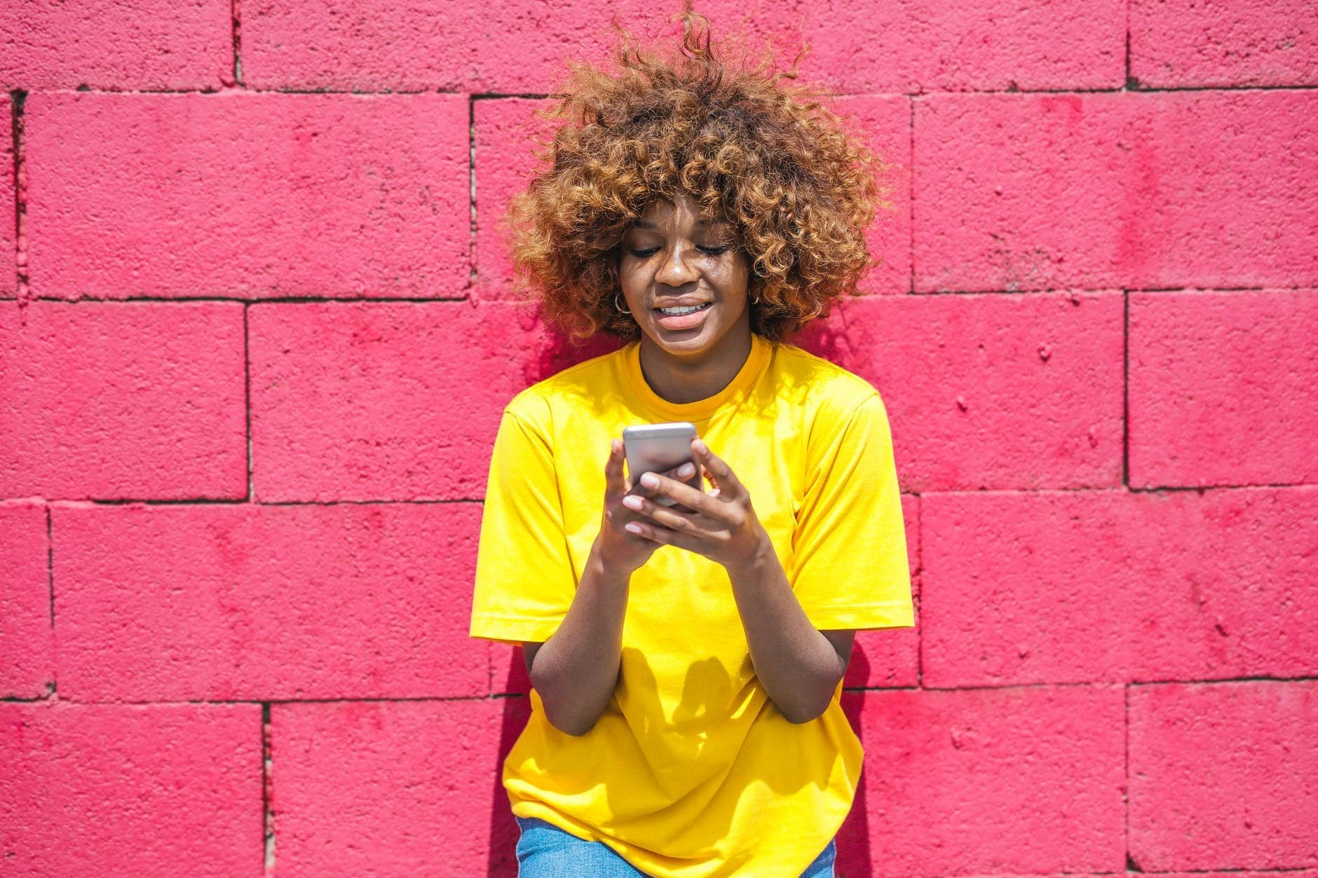 woman in yellow shirt holding cellular phone