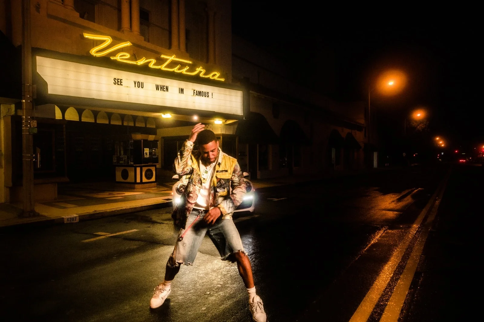 man in black and white jacket standing on road during night time