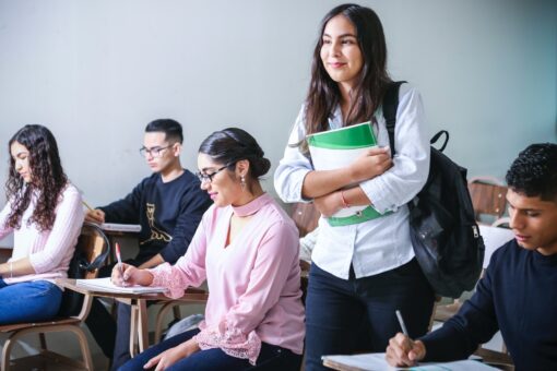 woman carrying white and green textbook