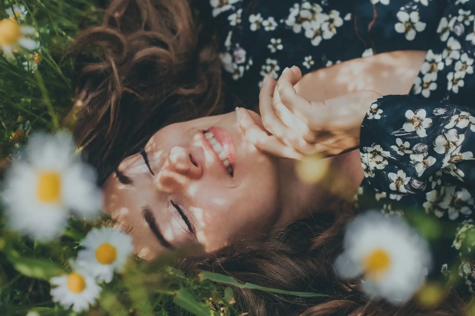 woman in black and white floral shirt lying on green grass field