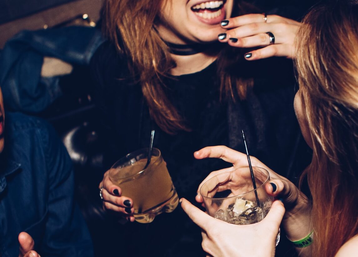 two women talking while holding drinking glasses