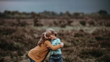 two child hugging in front of field