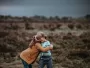 two child hugging in front of field