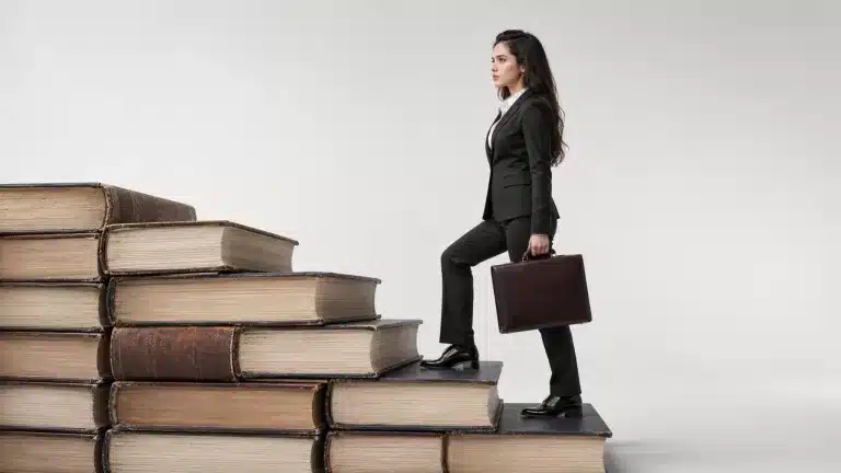женщина поднимается по лестнице из книг