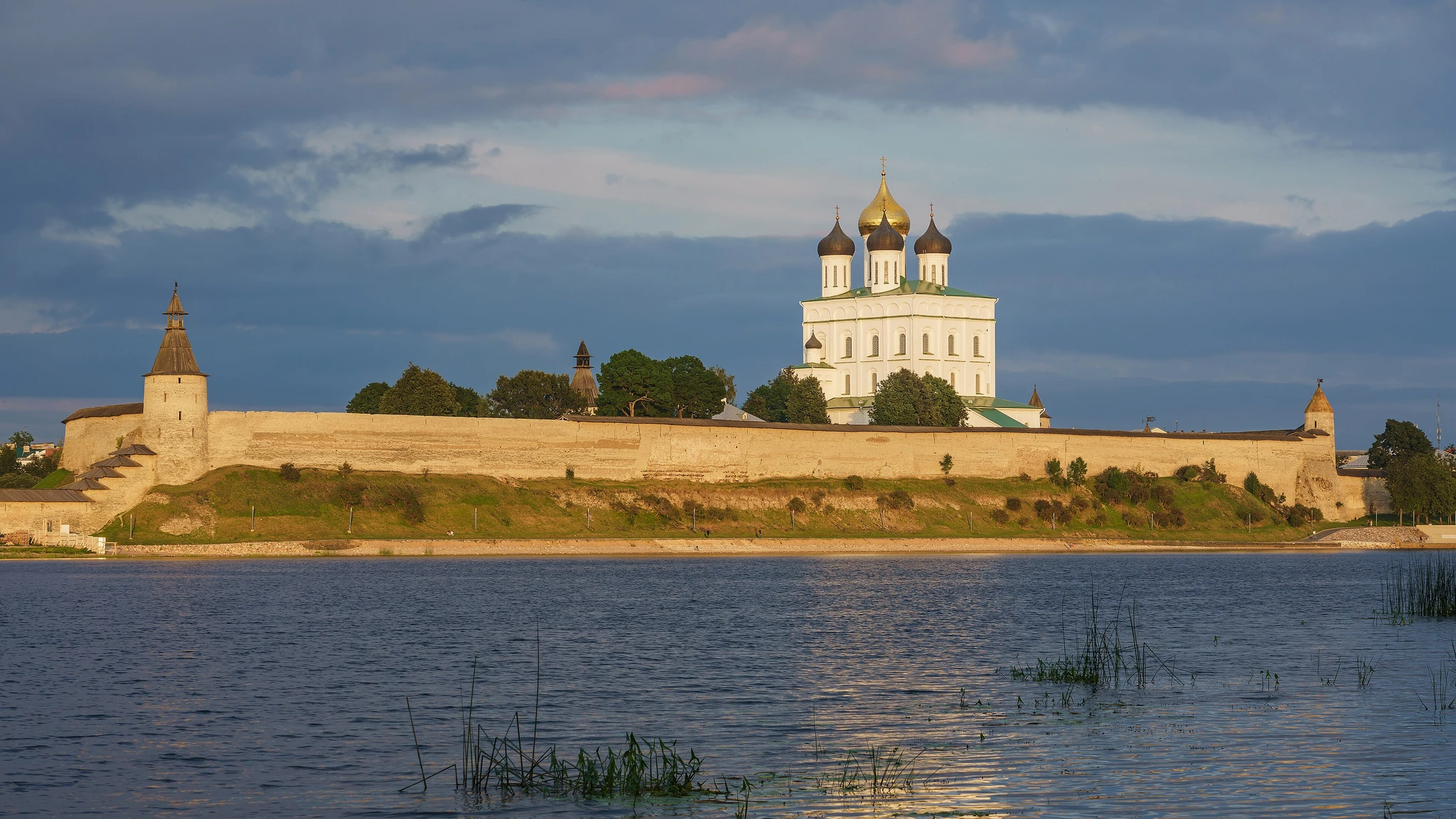 Каменные стены крепости и белый собор на берегу реки